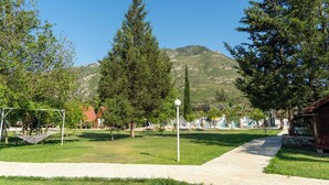 Un parque con un arco de fútbol, árboles, cielo despejado y montañas al fondo.