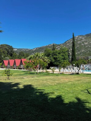 A hotel with red-roofed buildings, a swimming pool, and a mountainous backdrop. - Don Kişot Pansiyon (Kumluca)