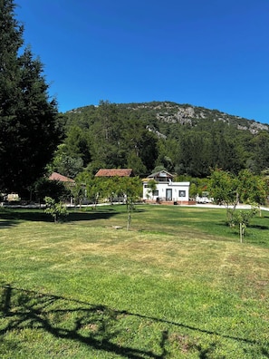 Un campo cubierto de césped con un edificio blanco y una estructura de techo rojo al fondo.