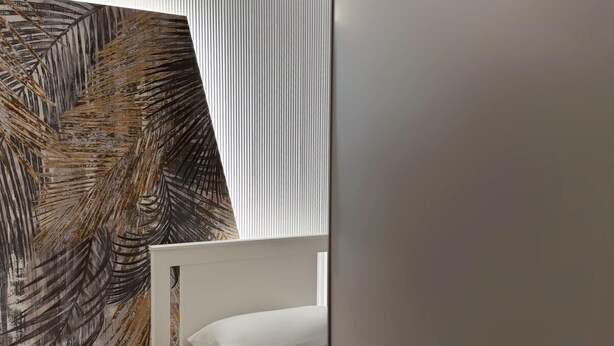 A bedroom with a bed, a nightstand, a wardrobe, and a wall with a leaf pattern. - Perfect house for Naples and Pompeii with balcony overlooking Vesuvius free parking (Casalnuovo di Napoli)
