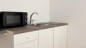 A kitchenette with a microwave, sink, and white cabinets. - Perfect house for Naples and Pompeii with balcony overlooking Vesuvius free parking (Casalnuovo di Napoli)