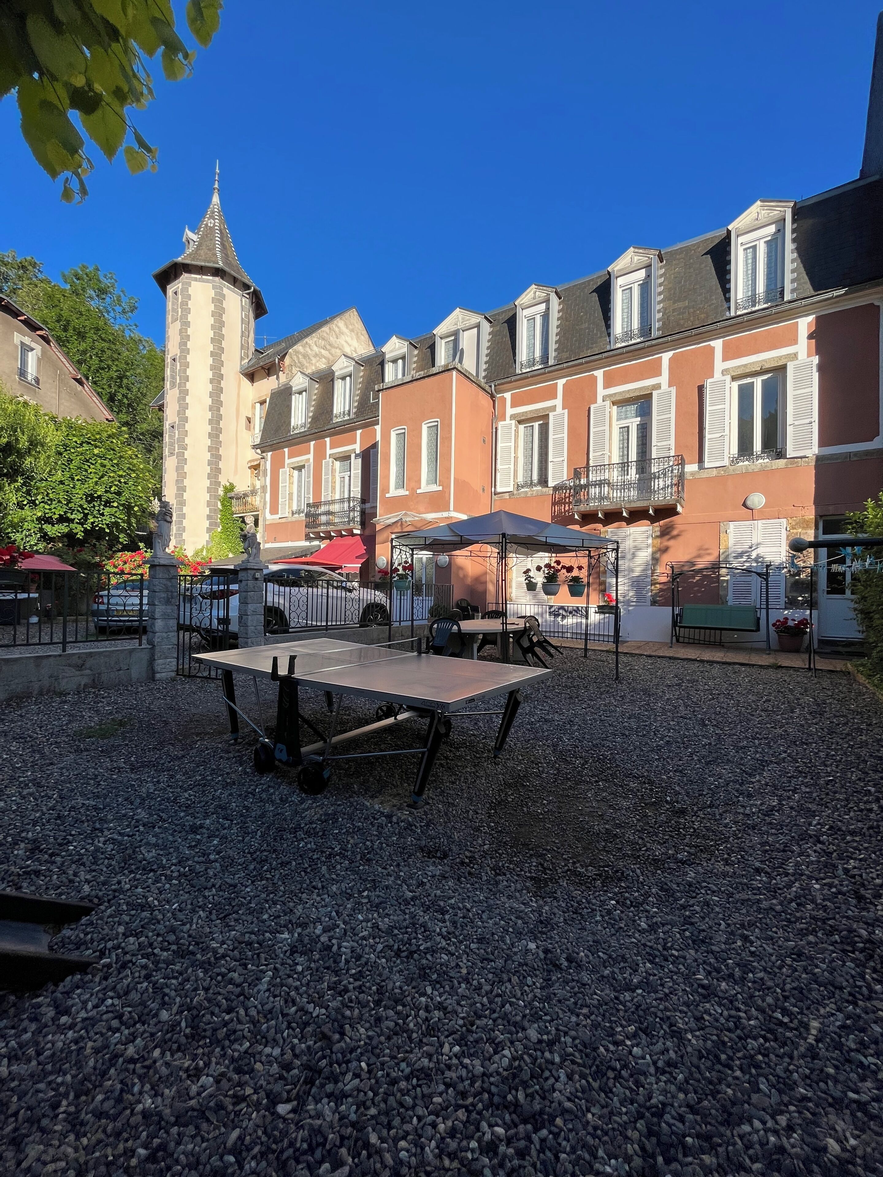 Un patio con una mesa de tenis de mesa, una torre y edificios con balcones.