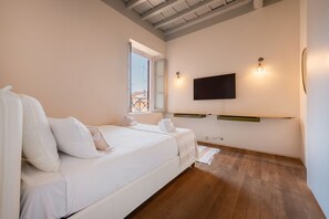 Ein Schlafzimmer mit Bett, einem an der Wand montierten Fernseher und einem Fenster.