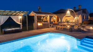 Una piscina con hidromasaje, asientos exteriores y un edificio de piedra con arcos.