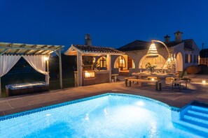 Ein Pool mit Whirlpool, Sitzgelegenheiten im Freien und ein Gebäude mit Bögen und Steinarchitektur.