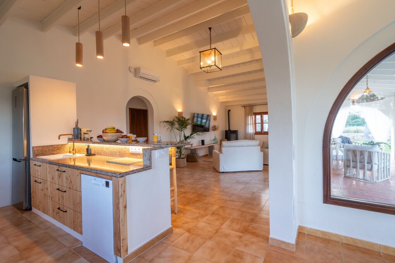 A spacious living area with a kitchen island, a fireplace, and a view through a large window.