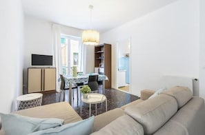 Ein modernes Wohnzimmer mit einer Couch, einem Esstisch und einem Fernseher.