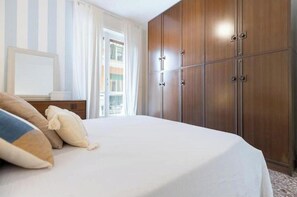 Ein Hotelzimmer mit einem Bett, gestreifte Vorhänge, einem Holzschrank und einem Fenster mit Blick.