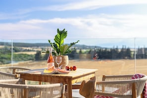 A wooden table with a bottle, glasses, and fruits, surrounded by wicker chairs, overlooking a scenic landscape. - Sani Gulf I & II (Kassandra)