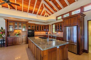 Eine geräumige Küche mit Holzschränken, einer Arbeitsplatte aus Granit und einem großen, edlen Kühlschrank aus Edelstahl.