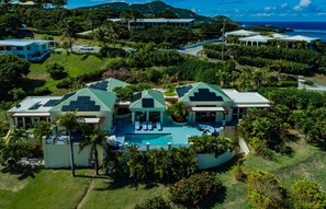 Ein großes Resort mit mehreren Gebäuden, einem zentralen Pool und üppiger Bepflanzung.
