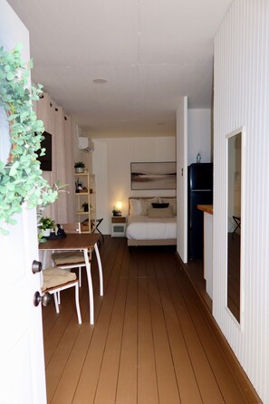 Ein kleines Zimmer mit einem Bett, einem Nachttisch und einem kleinen Schreibtisch mit Stuhl.