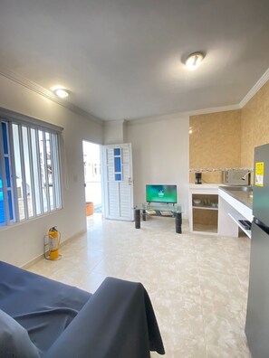 Een moderne keuken met een ingebouwde oven, een eethoek met een tafel en een televisie op de achtergrond.