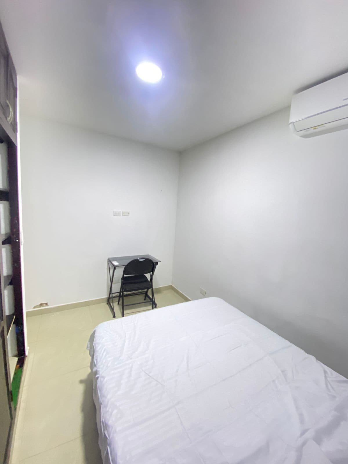 A small, clean room with a bed, a desk, and a chair.