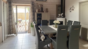 Un espace repas avec une longue table, des chaises, une plante en pot et un tableau accroché au mur.
