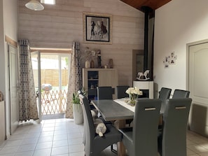 Ein Essbereich mit einem langen Tisch, Stühlen, einem Blumentopf und einem Gemälde an der Wand.