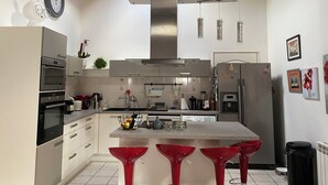 Une cuisine moderne dotée d’un îlot central, d’appareils électroménagers en acier inoxydable et d’un plafond en bois.