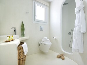 A bathroom with a bathtub, a toilet, a sink, and a window. - Delmar Apartments and Suites (Milos)
