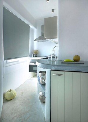 A modern kitchen with a built-in island, stainless steel appliances, and a minimalist design. - Delmar Apartments and Suites (Milos)