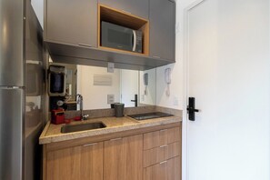 Eine Küche mit Kühlschrank, Mikrowelle, Spüle und Holzschränken.