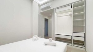 A modern bedroom with a large bed, a walk-in closet, and a hallway leading to another room. - Hostdomus - Princess Suite (Marina di Andora)