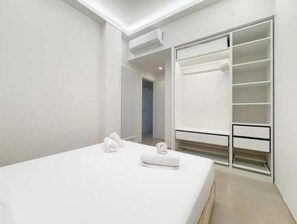 Ein modernes Schlafzimmer mit einem großen Bett, einem begehbaren Kleiderschrank und einem Flur, der zu einem anderen Raum führt.