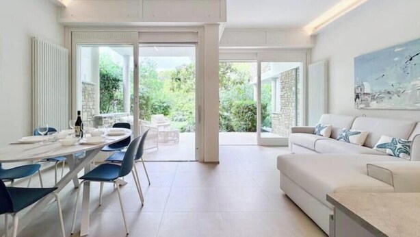 A modern living room with a dining area, a sofa, and a painting on the wall. - Hostdomus - Princess Suite (Marina di Andora)