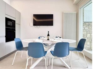 Eine moderne Küche mit Einbaugeräten, einem Esstisch mit Stühlen und einem Wand-Fernseher.