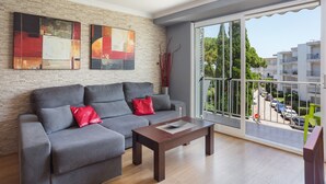 A living room with a grey sofa, a wooden coffee table, and two abstract paintings on the wall. - Apartment 'Ducal Mar' with Shared Garden, Wi-Fi and Air Conditioning (Grau i Platja)