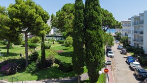A residential street with parked cars, tall trees, and a clear blue sky. - Apartment 'Ducal Mar' with Shared Garden, Wi-Fi and Air Conditioning (Grau i Platja)