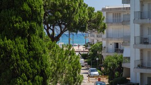 A coastal residential area with multi-story buildings, a tree-lined street, and a view of the sea. - Apartment 'Ducal Mar' with Shared Garden, Wi-Fi and Air Conditioning (Grau i Platja)