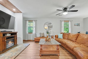 A living room with a fireplace, leather sofa, and a television. - Refresh and Renew at Margaret’s Place on Lake Chatuge! (Hiawassee)