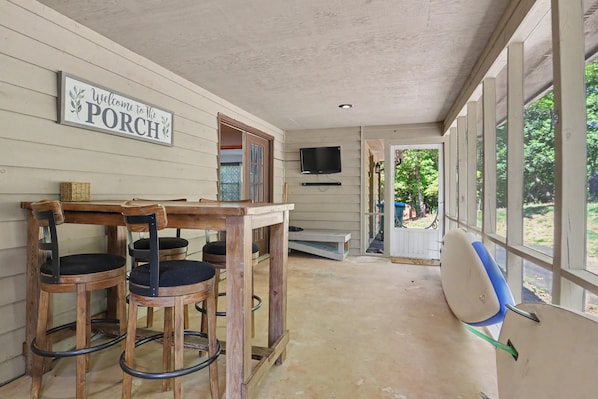 A porch with a sign, wooden chairs, a table, and a TV mounted on the wall. - Refresh and Renew at Margaret’s Place on Lake Chatuge! (Hiawassee)