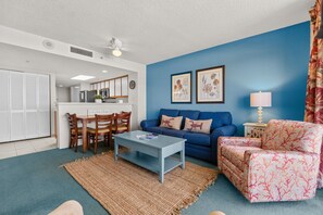 Ein Wohnzimmer mit einem blauen Sofa, einem gemusterten Sessel, einem Couchtisch und einem Teppich.