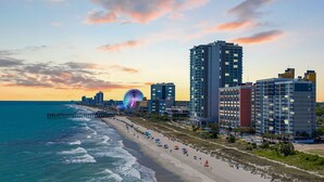 A coastal cityscape with a beach, a Ferris wheel, and high-rise buildings. - Oceanfront 2BR 2BA, Pools, Hot Tub, Epic Views (Myrtle Beach)