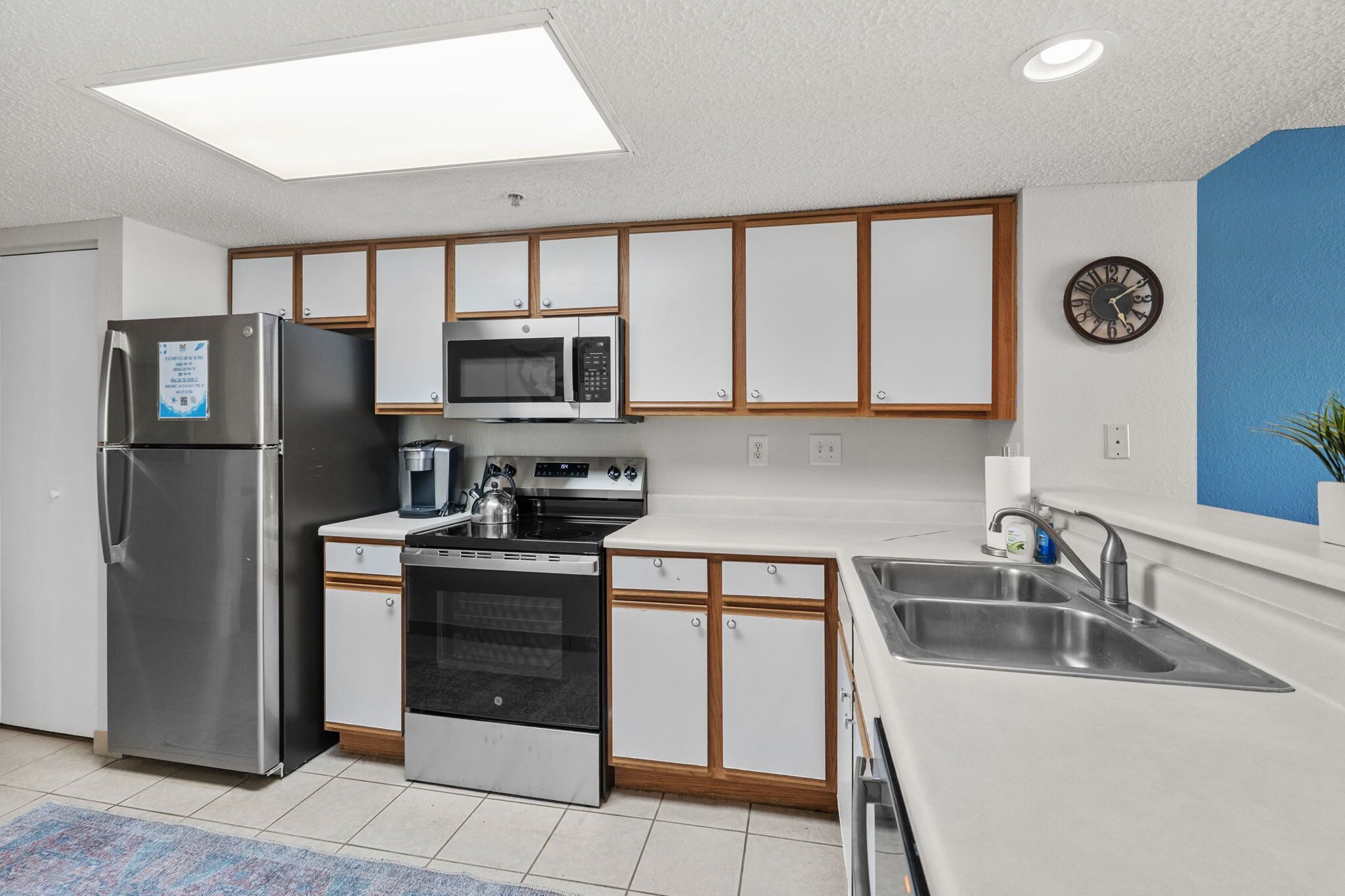 A modern kitchen with stainless steel appliances, wooden cabinets, a microwave, stove, and a sink.