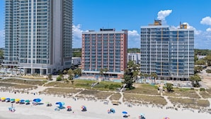 A beachfront hotel with multiple high-rise buildings, a sandy beach, and a pool area. - Oceanfront 2BR 2BA, Pools, Hot Tub, Epic Views (Myrtle Beach)