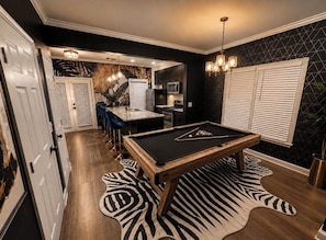 A pool table with a zebra print rug, a kitchen area with a microwave, and a dining area with a bar stool. -     Luxury Atlanta Host Stylish Stays Designed for Comfort & Experience (Atlanta)
