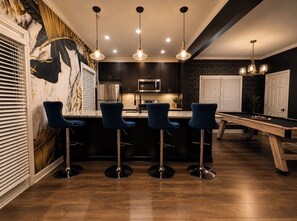 A modern kitchen with dark cabinetry, a central island, and bar stools. -     Luxury Atlanta Host Stylish Stays Designed for Comfort & Experience (Atlanta)