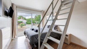 A bedroom with a bed, a TV mounted on the wall, a wooden ladder, and a sliding door leading to an outdoor area. - Villa Joël – House with Private Pool, 10 Minutes from the Beach (La Jonchère)