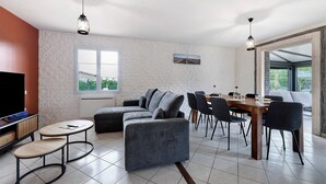 A modern living room with a sectional sofa, a dining table with chairs, and a TV. - Villa Joël – House with Private Pool, 10 Minutes from the Beach (La Jonchère)