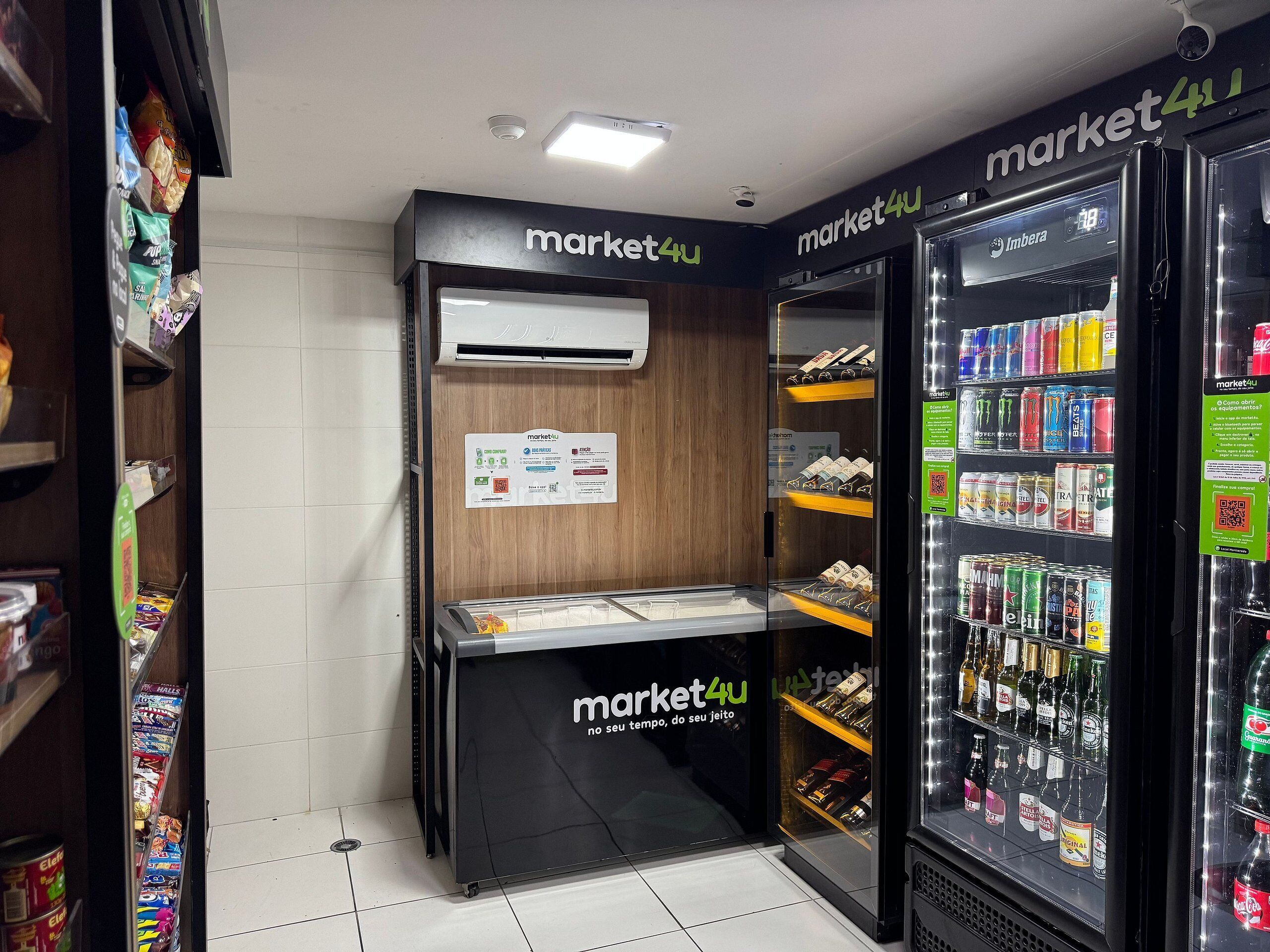 A self-service kiosk with a digital screen and a refrigerated display case with beverages.