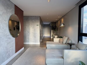 A modern hallway with a sofa, a mirror, and a potted plant.