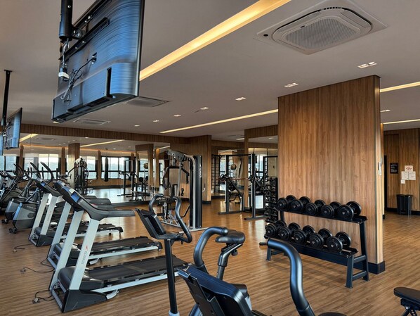 A gym with treadmills, weight machines, and dumbbells.