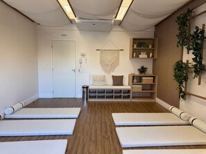 A room with a wooden floor, a white bench, a white door, and a wall-mounted shelf with plants. - Studio recém-construído no coração da Vila Olímpia (São Paulo)