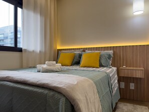 A neatly made bed with pillows, a bedside table, and a wall-mounted light fixture.