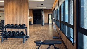 Ett gym med trägolv, utrustning för styrketräning och stora fönster.