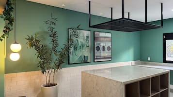 A kitchen with a central island, hanging plants, and a tiled backsplash.
