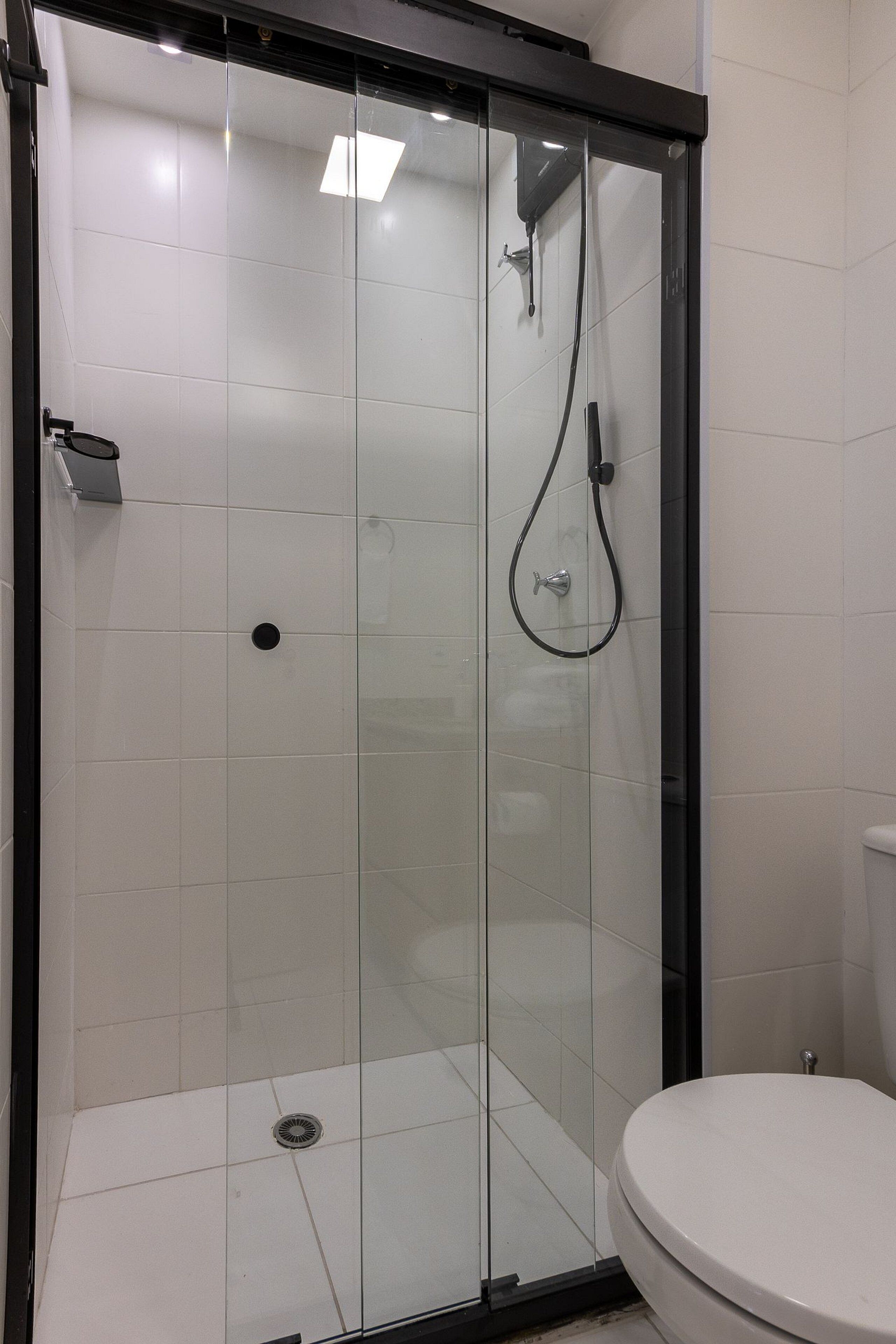 A glass-enclosed shower stall with a toilet adjacent to it.