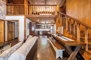 A spacious kitchen with wooden accents, a dining area with a bench, and a staircase leading to a loft. - Pottsboro Lodge - Sleeps 15 - Hot Tub & Patio (Pottsboro)